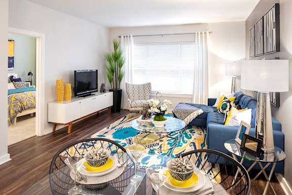 A living room with a blue couch and a glass table with plates on it.