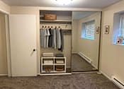 Thumbnail 7 of 8 - A white closet with clothes hanging up and a basket on the shelf.
