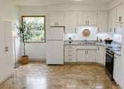 Thumbnail 3 of 8 - A kitchen with white cabinets and a marble floor.
