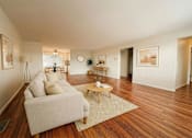 Thumbnail 5 of 8 - A living room with a white couch and wooden floors.