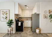 Thumbnail 8 of 8 - A kitchen with a black fridge and white cabinets.