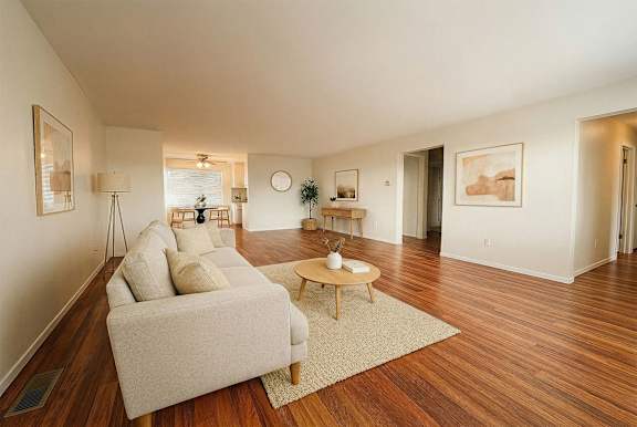 A living room with a white couch and wooden floors.