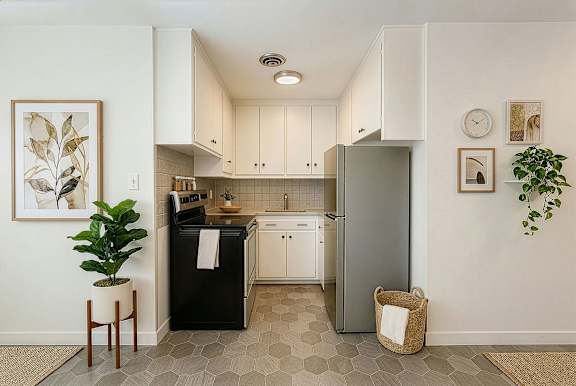 A kitchen with a black fridge and white cabinets.