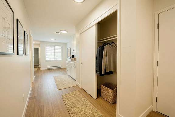 A hallway with a white door and a brown rug.