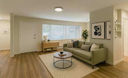 A living room with a couch, a coffee table, and a plant.