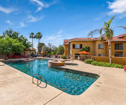 A swimming pool surrounded by palm trees and a building.