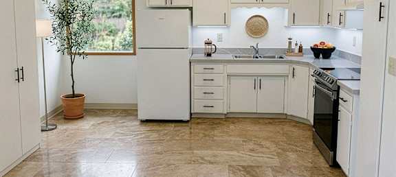 A kitchen with white cabinets and a marble floor.