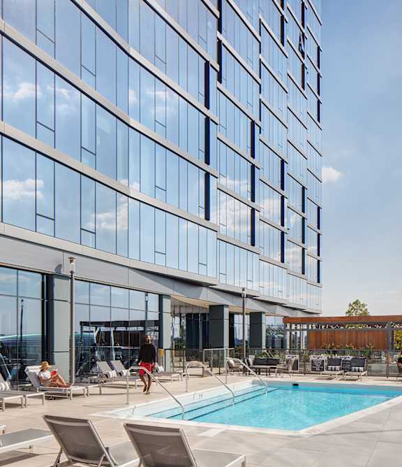 A large glass building with a pool in front.