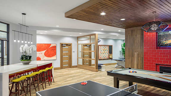 A ping pong table is in the middle of a room with a bar and a pool table.