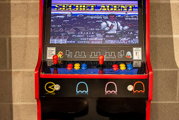 A red arcade machine with a screen showing a game called Shecht Agent.