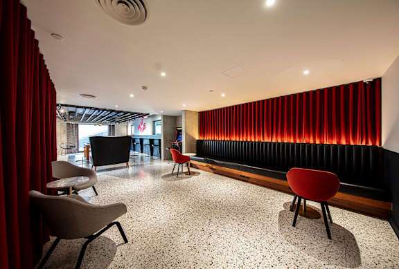 A room with red curtains and a black sofa.