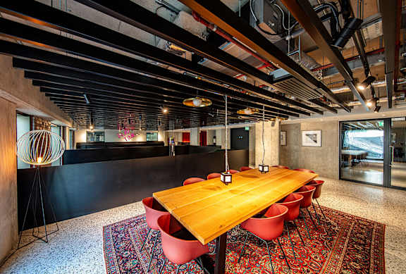 A long wooden table with red chairs is in the middle of the room.