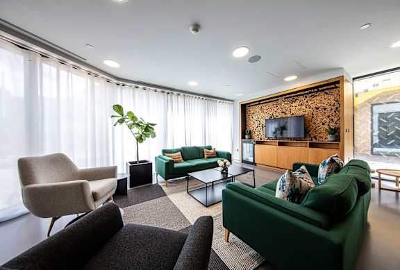 A living room with a green couch and a wooden cabinet with a TV on it.