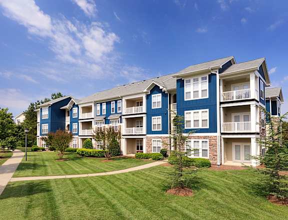 an apartment building with a green lawn and a blue sky
