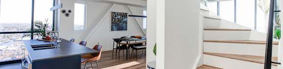 a living room with a staircase and a table and a kitchen