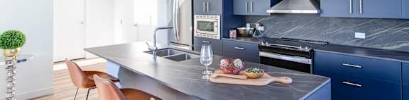 a kitchen with blue cabinets and a marble counter top