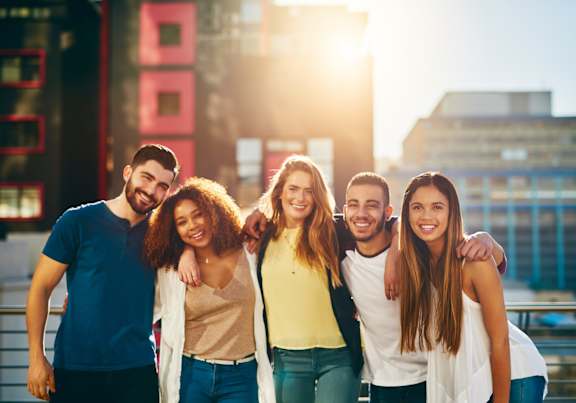 A group of five friends are standing together on a bridge.