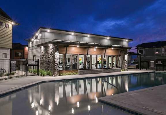 A building with a pool in front of it at night.