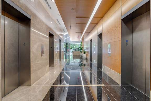 A long hallway with marble floors and elevators on either side.