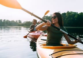 Man and Woman Kayaking on River and Smiling