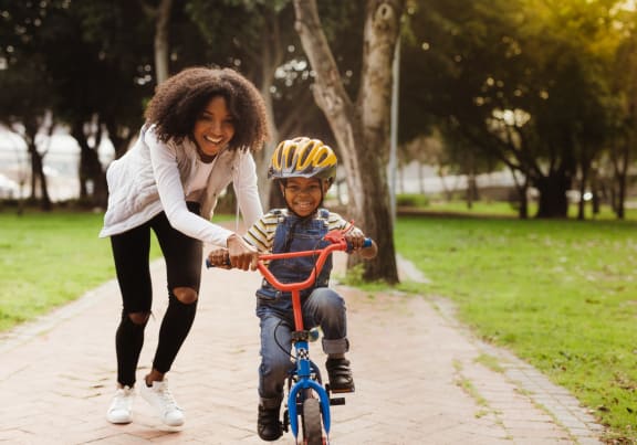 Woman Pushing Little Boy on Bicycle Smiling