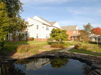 A white house with a pond in front of it.