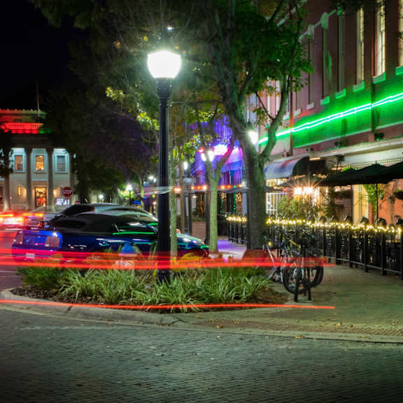 A long exposure shot of a city street at night with light trails from moving vehicles.