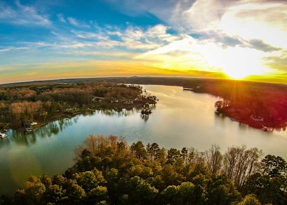 A beautiful sunset over a lake with boats and trees.