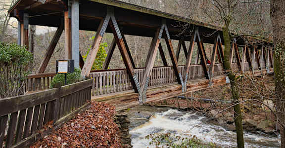 A wooden bridge over a river with a sign on it.