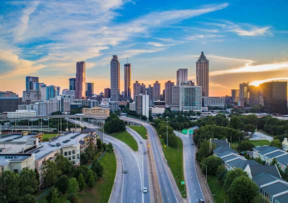A cityscape with a highway in the foreground and buildings in the background.
