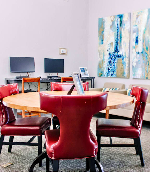 A conference room with a table surrounded by chairs and a painting on the wall.