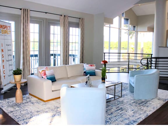 A living room with a white couch and a blue and white rug.