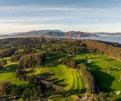 A golf course with a view of the ocean and mountains in the distance.