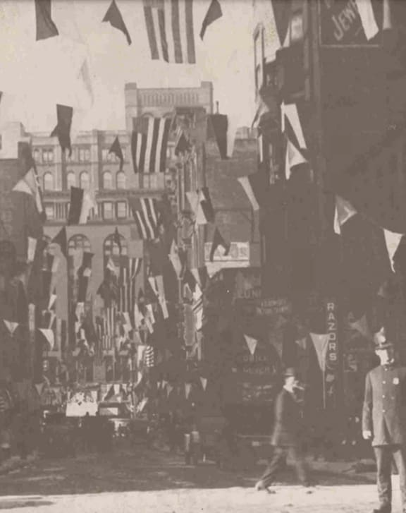 a crowd of people walking down a street with flags at East 4th Street, Cleveland, 44115