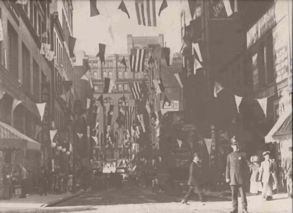 a crowd of people walking down a street with flags at East 4th Street, Ohio, 44115