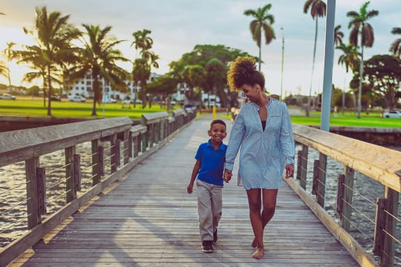 a woman and a boy walking on a wooden bridge
