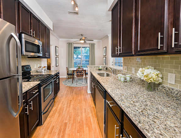 A kitchen with dark wood cabinets and granite countertops.