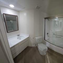 A white bathroom with a toilet, sink, and shower.