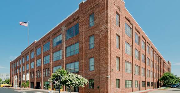 a large brick building with an flag in front of itat Tindeco Wharf, Baltimore Maryland
