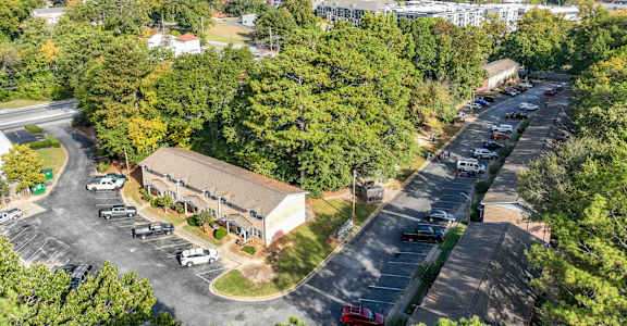 A parking lot with a building in the background and trees surrounding the areaat Waverly Manor Townhomes, Norcross, GA  .