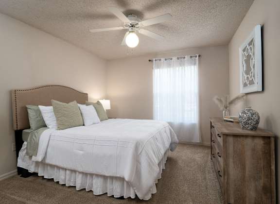 a bedroom with a large white bed and a ceiling fan at The Fountains Apartments, Pensacola, FL