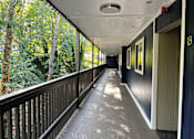 Thumbnail 6 of 8 - A long balcony with a railing and a view of trees.