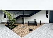 Thumbnail 14 of 16 - a metal bench in front of a white building with a staircase