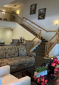 A living room with a couch, chairs, and a staircase.