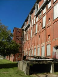Converse Mill before renovation—historic red brick exterior with multiple windows and basement doors.