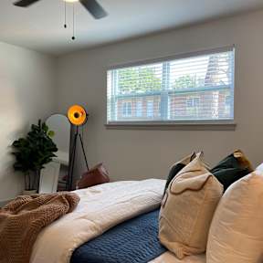 A bedroom with a bed, pillows, a fan, and a window.