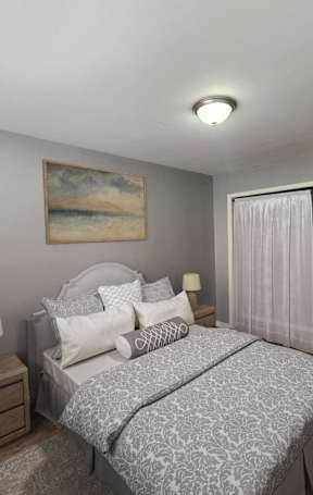 A bedroom with a bed, nightstand, and a painting on the wall.