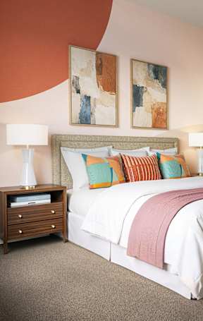 A bedroom with a large bed and two lamps.