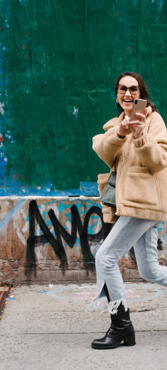 a woman running down the street while looking at her cell phone