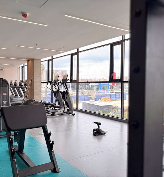 A gym with a variety of equipment including treadmills, weights, and exercise machines.